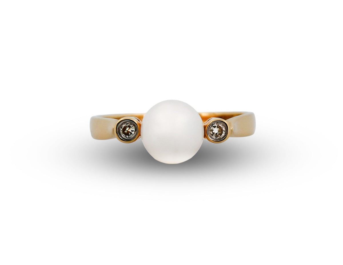 Gold ring with a large white stone and smaller brown stones on a white background