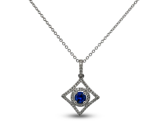 A silver-toned diamond pendant necklace featuring a central round-cut deep blue sapphire surrounded by a halo of small diamonds, set within a larger diamond-shaped frame on a delicate chain.