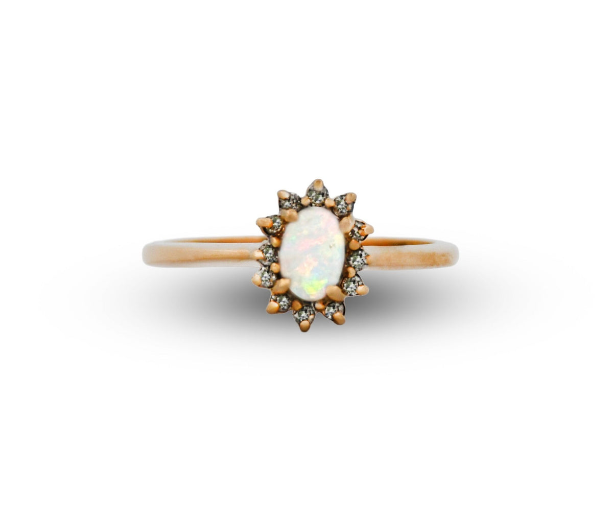 Gold ring with a central opal stone and smaller diamonds on a white background