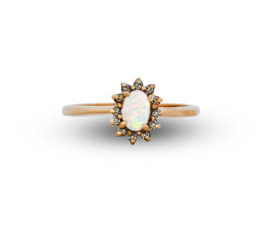 Gold ring with a central opal stone and smaller diamonds on a white background
