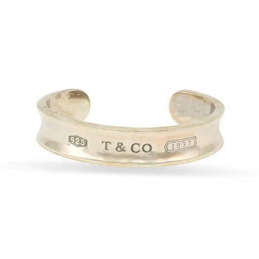 Silver open bangle with 'T & Co' engraving on a white background