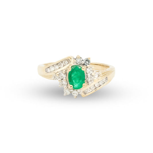 Gold ring with a green gemstone and diamonds on a white background